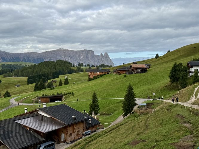 Hikers on the Alpe di Siusi trail make their way passing homes and chalets in Europe's largest high-elevation meadow