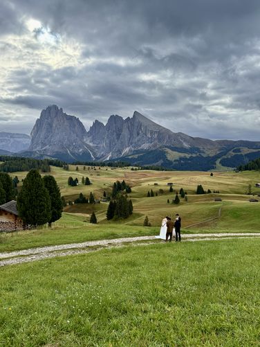 A bridge and groom stand near Belvedere dell'Alpe di Siusi for wedding photos