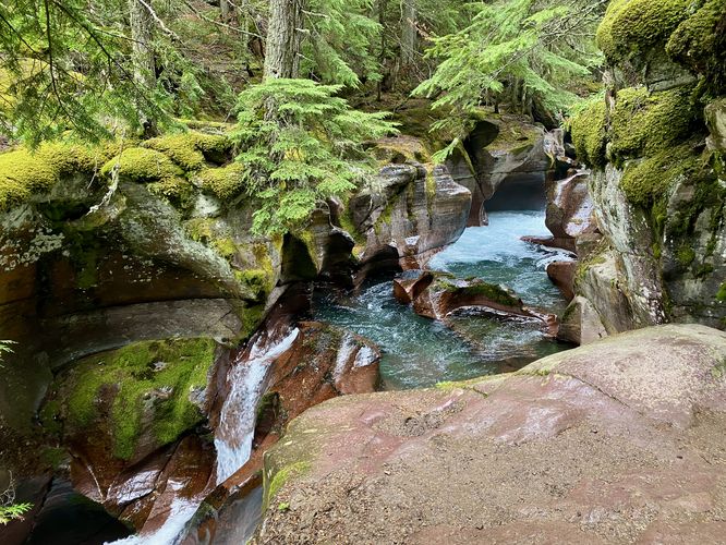 Waterfall in Avalanche Creek, turquoise water, and moss-covered gorge