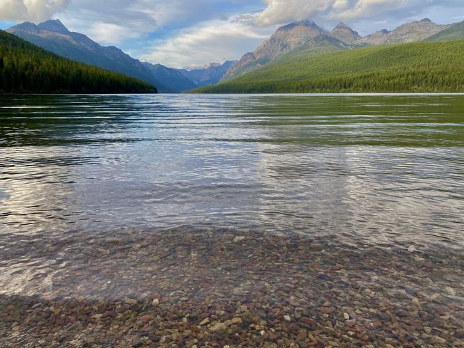 Colorful rocks in Bowman Lake with alpine mountains in the distance