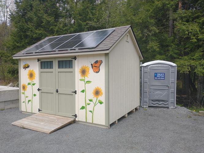 Restroom for visitors is installed nest to a shed.