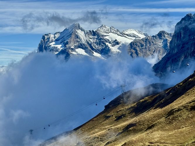 View of the Eiger Express cable cars ascending through clouds