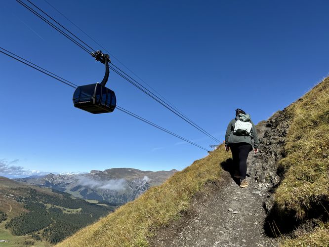 Hiking the Eiger Trail along steep slopes with the Eiger Express passing by