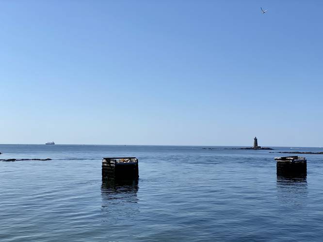 View of submarine net cribs and lighthouse from the pier