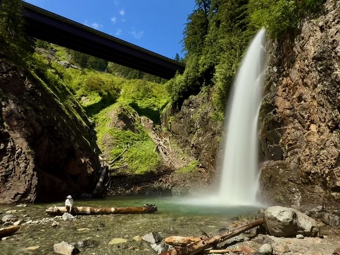 Long exposure of Franklin Falls with a man sitting on a fallen tree in view