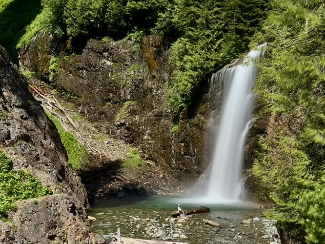 Long exposure of Franklin Falls from high up on the trail with a man sitting on a fallen tree in view