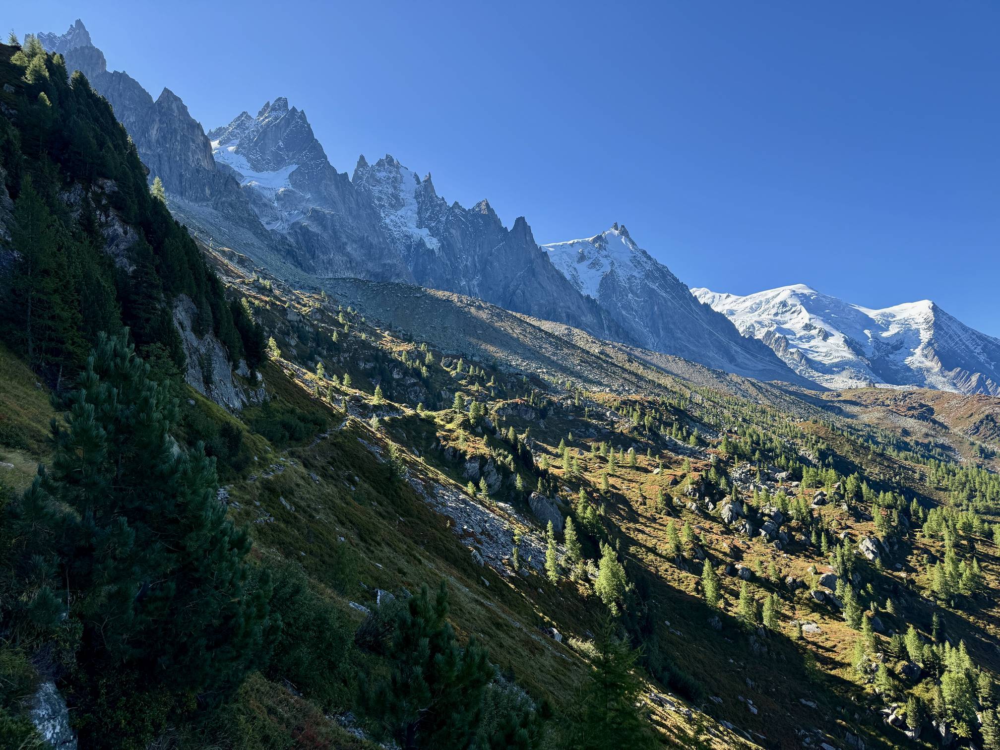 Snow-capped jagged alpine peaks tower over the trail that runs along the Mont Blanc massif above the Chamonix Valley, France.