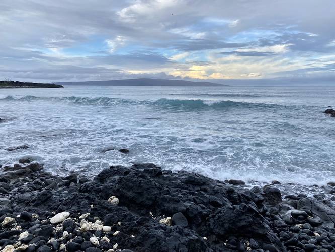 Waves crash ashore with the island of Kaho'olawe in the distance