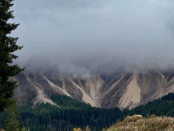 Alpine mountains of the Dolomites sit in the clouds above Lago di Carezza