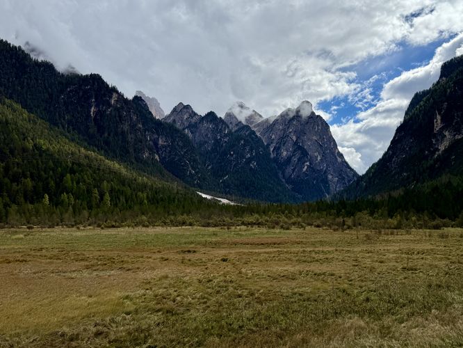 View of alpine peaks from the sprawling meadow of Lake Dobbiaco