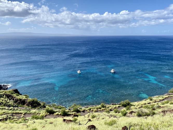 Turquoise-colored Hawaiian ocean below with snorkel tour boats floating over coral
