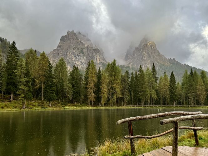 A wooden footbridge and sunlit alpine peaks in the Dolomites at Lake Antorno