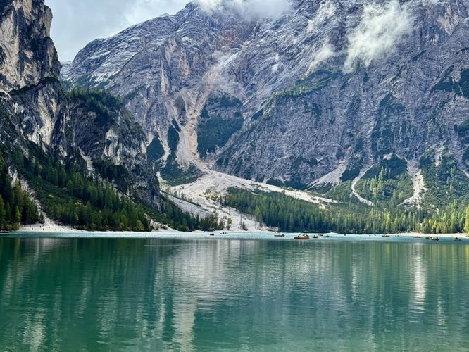 Row boats floating in Lago di Braies (Lake Braies) with towering alpine mountains in the background