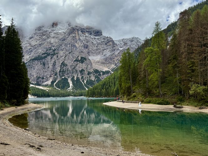 A bride and groom stand along the turquoise waters of Lago di Braies