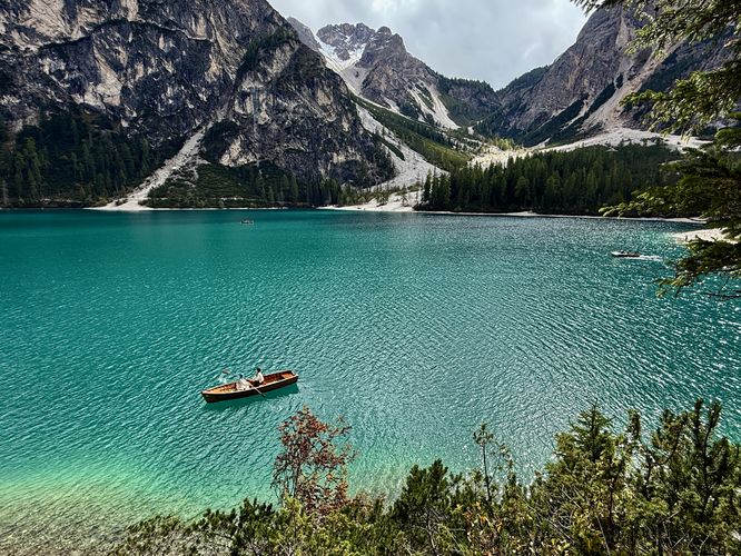 A rowboat and passenger with blue hair sits in the turquoise waters of Lake Braies