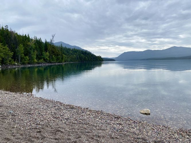 South-facing view of Lake McDonald with glassy water and colorful rocks