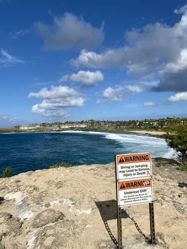Warning sign at Makawehi Point - undermining, calving, and undercut cliffs could lead to accidental death or injury if the cliff falls