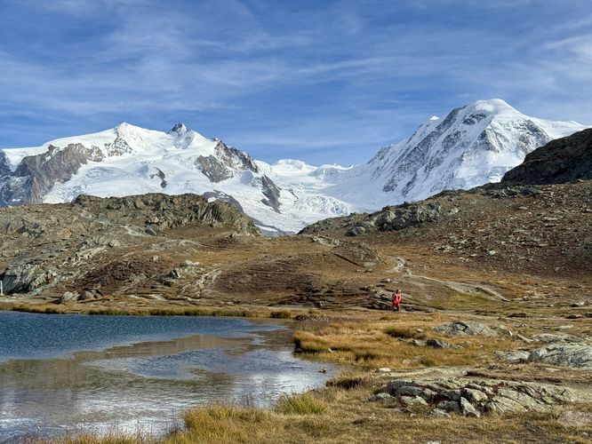 A hiker walks past Riffelsee with the Monte Rosa massif in the background