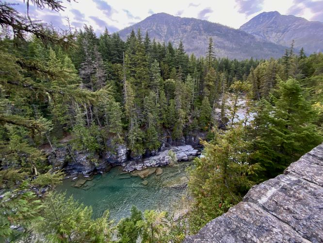 Mountains and evergreen forests surround McDonald Creek just south of McDonald Falls
