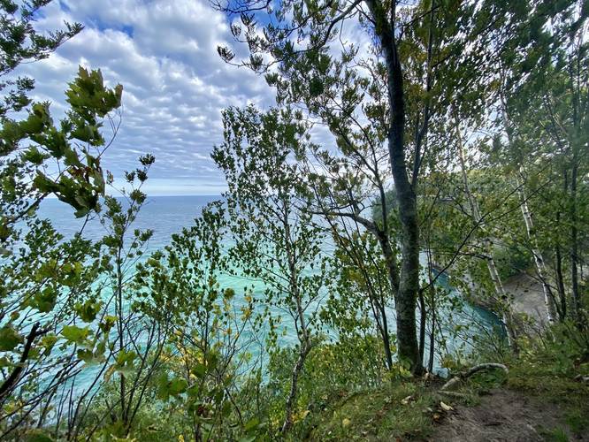 Lake Superior's turquiose water shines through the canopy near the cliffs of Pictured Rocks National Lakeshore