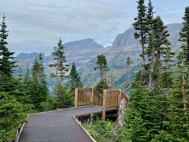 Stairs lead down to the viewpoint with the alpine mountains of the Garden Wall ahead