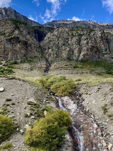 Portrait view of View of Piegan Falls in full with spillway to Going-to-the-Sun Road
