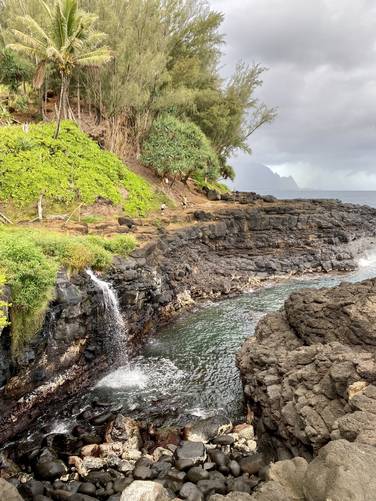 Waterfall spills into tide pool along Kauai coast