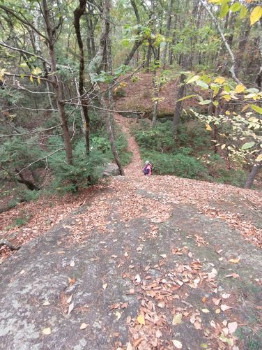 Third hiker attempts the climb up the rocky face of the ledge
