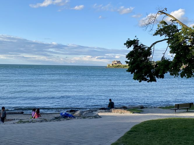 Visitor sits along Lake Ontario at Royal Queens Park