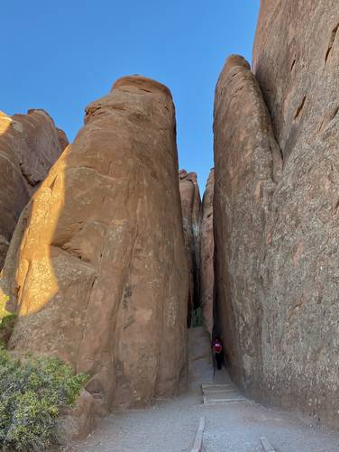 Trail passes through tall cliffs of Arches' rocky out croppings