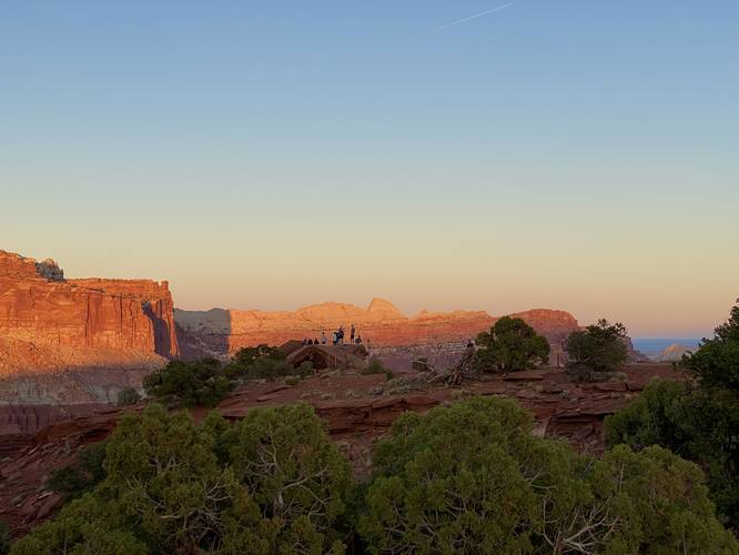 Hikers standing on Sunset Point rock for sunset