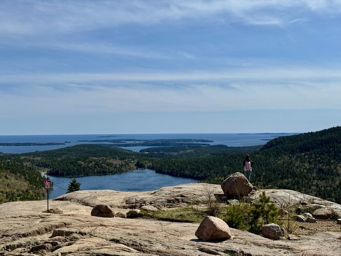 Hiker stands with a view of Jordan Pond from South Bubble