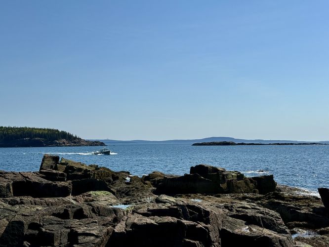 Boat in the foreground with a view of Great Head, Old Soaker island, and Schoodic Head mountain