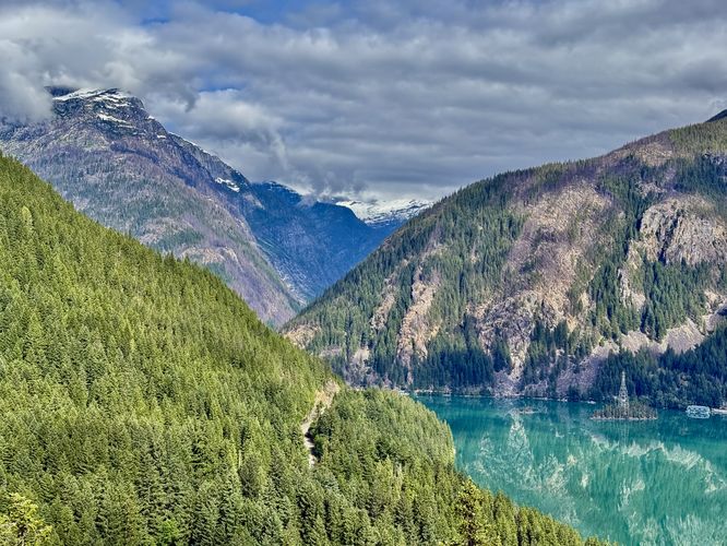 View of Diablo Lake's turquoise waters sitting next to the North Cascades Highway with Davis Peak overhead