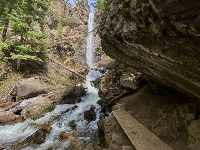 Bench under a cliff overhang with view of Treasure Falls