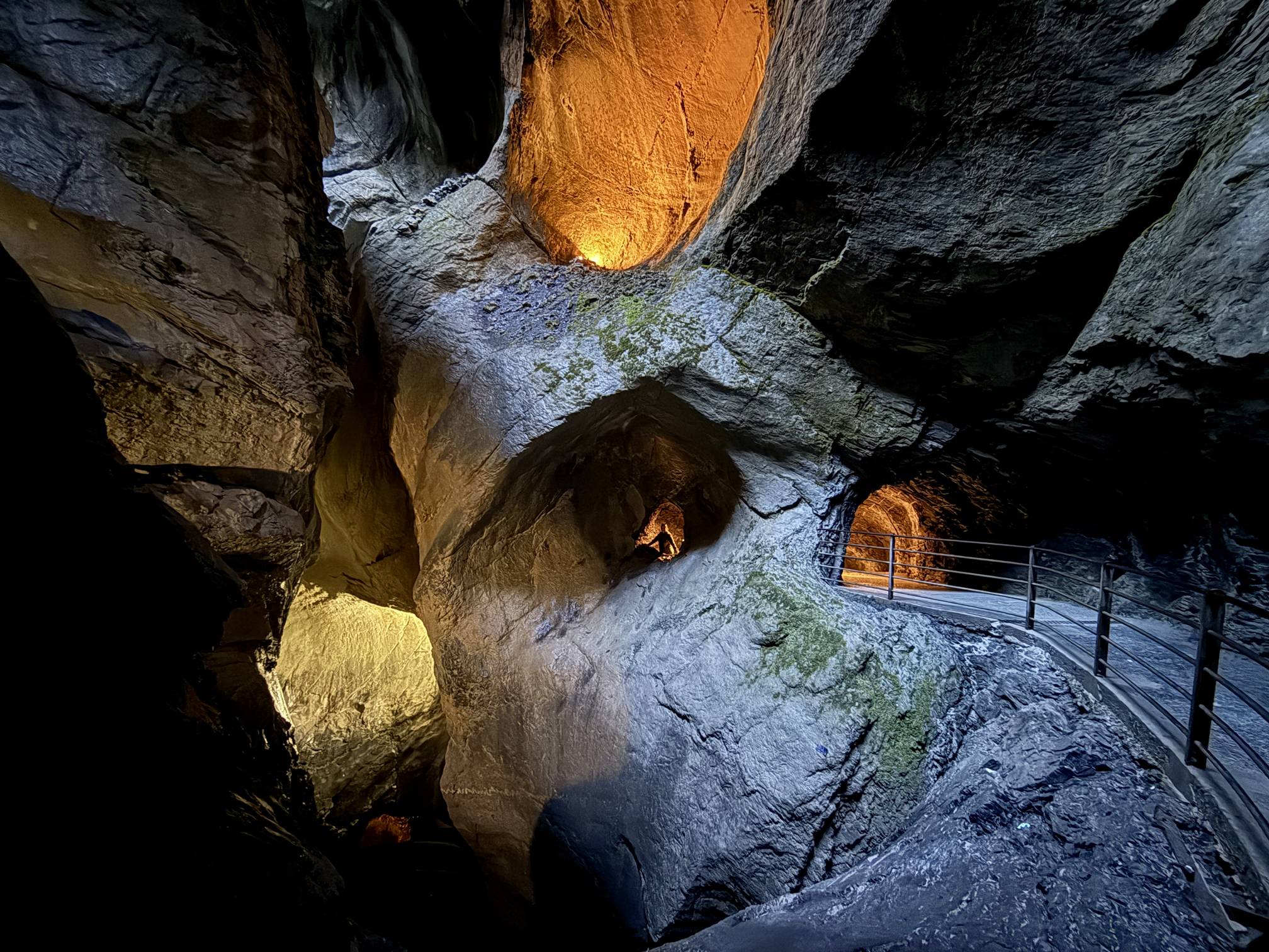 A hiker stands in a rock wall window carved out by glacial melt water over eons at Trümmelbach Falls in Lauterbrunnen Valley, Switzerland.
