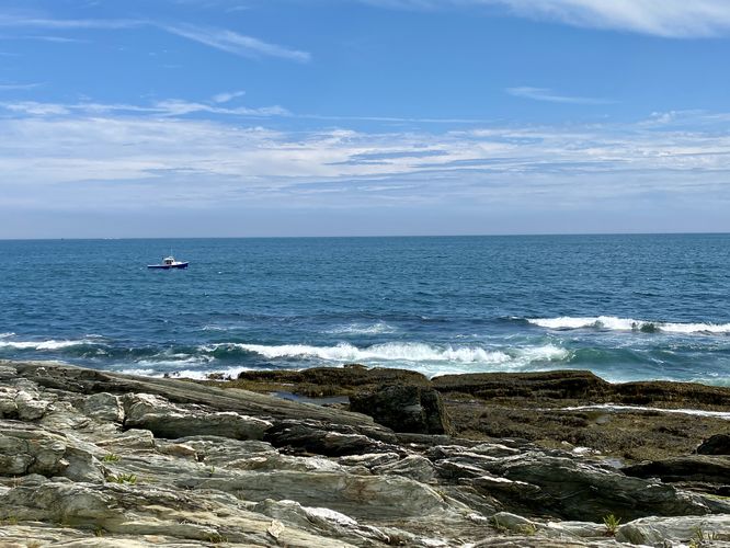 Boat in the ocean with cashing waves at Trundy Point