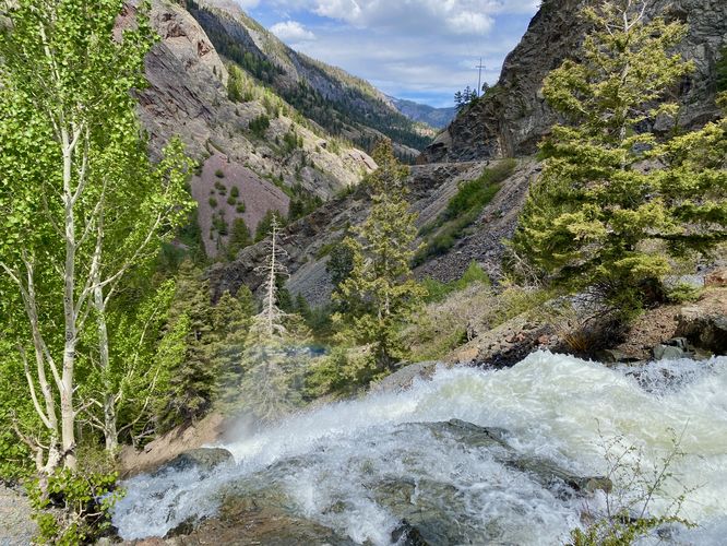 Rainbow dashes above Uncompahgre Falls with a view toward Ouray