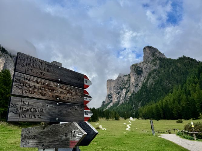 Trailhead sign for Vallunga (Langental) with a scenic backdrop of alpine peaks